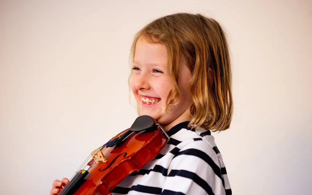 A happy girl, smiling, whilst playing the violin