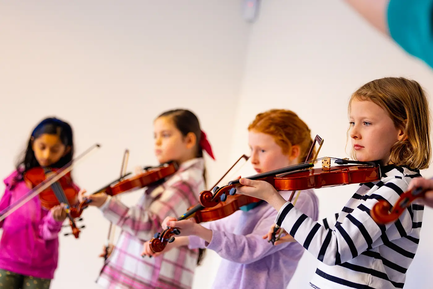 4 young girls learning to play the violin